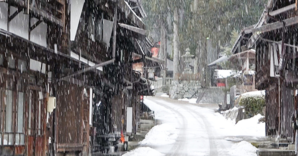 雪が降り白くなりつつある街道沿いの街並